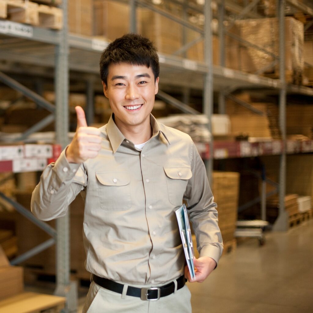 Male Chinese warehouse worker giving the thumbs up