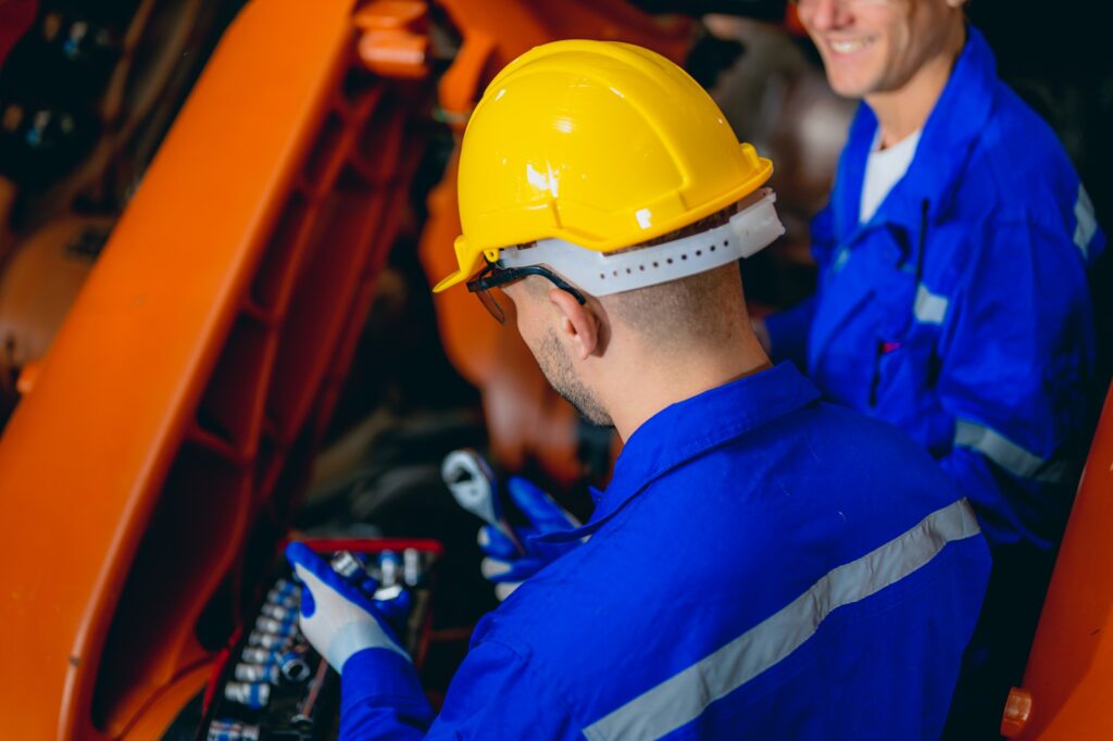 Professional maintenance worker with machine robotic arms at industrial factory