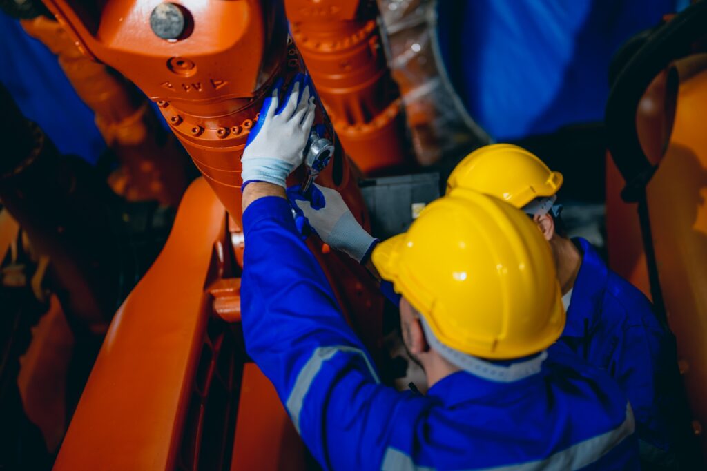 Professional maintenance worker with machine robotic arms at industrial factory